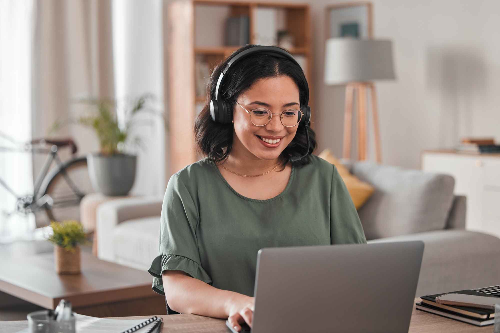 eine Frau sitzt an einem Tisch mit einem Laptop vor orangenem Hintergrund